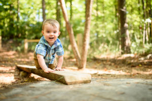 A small boy climbs on a board toward the camera.